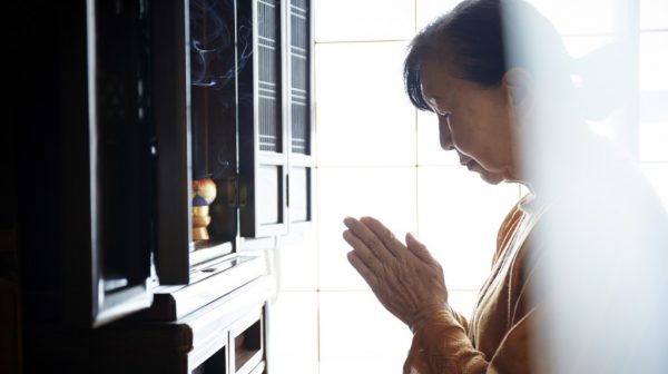 仏壇に手を合わせるシニア女性