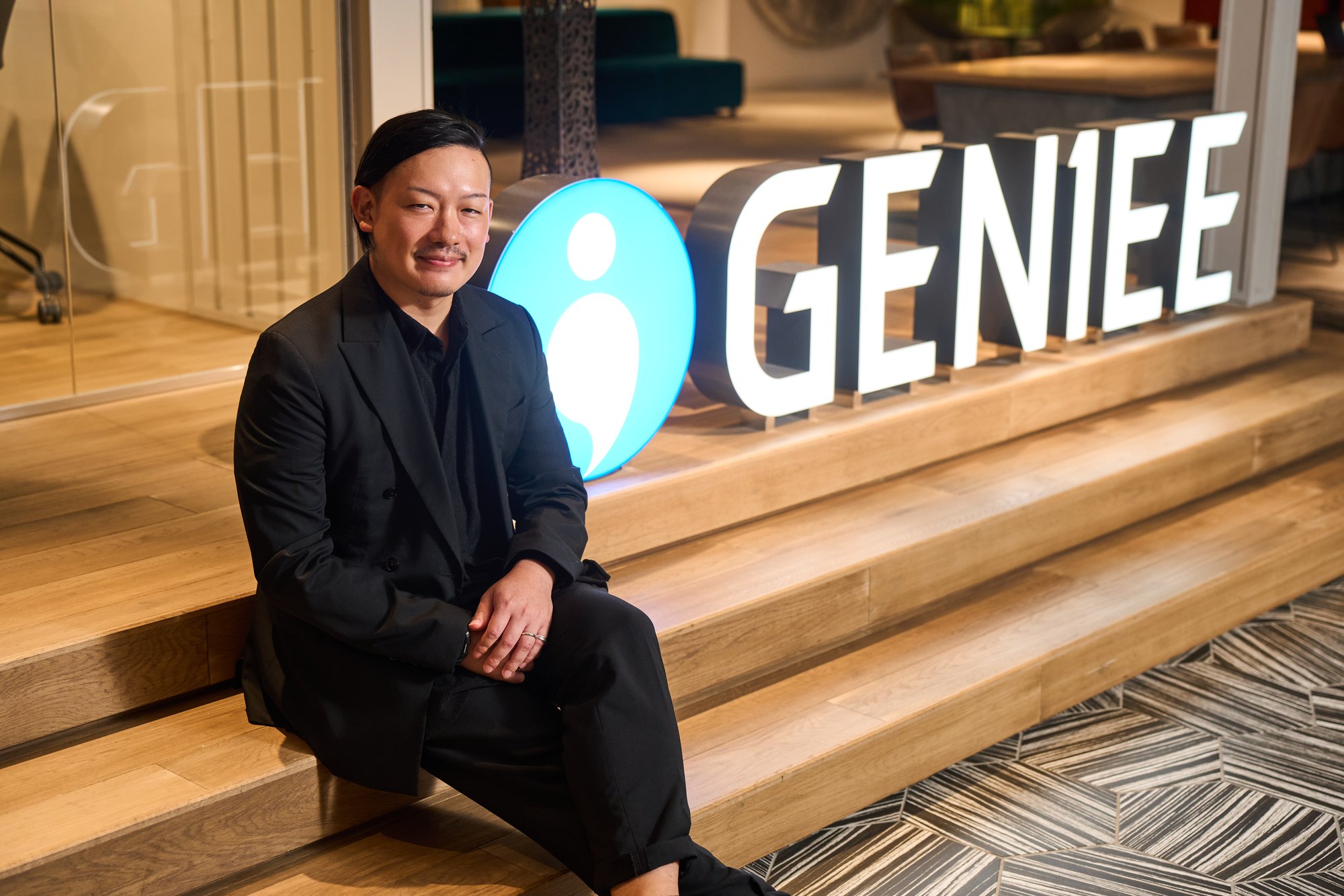 GENIEEのロゴの横に座る長島崇斗氏
